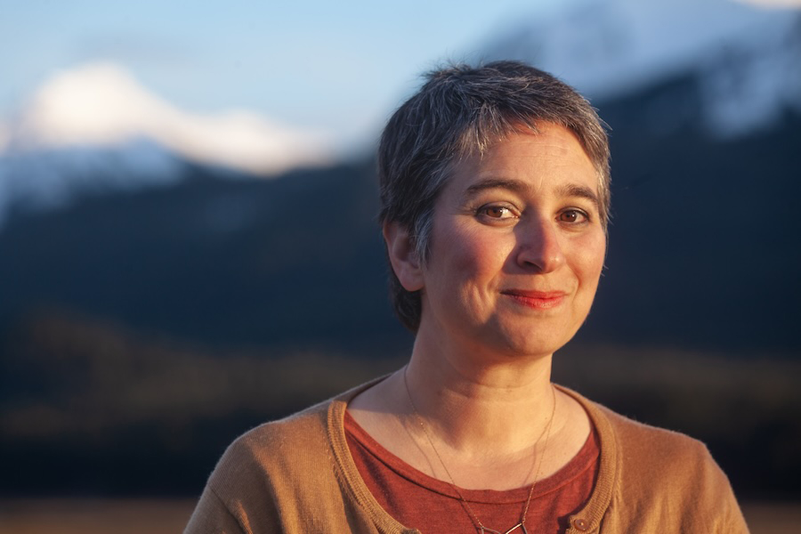 A woman smiles at the camera in front of a blurred background.