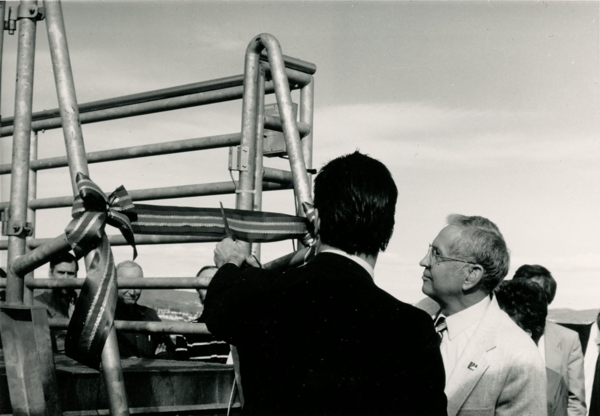 A man looks at a ribbon tied around a metal railing.
