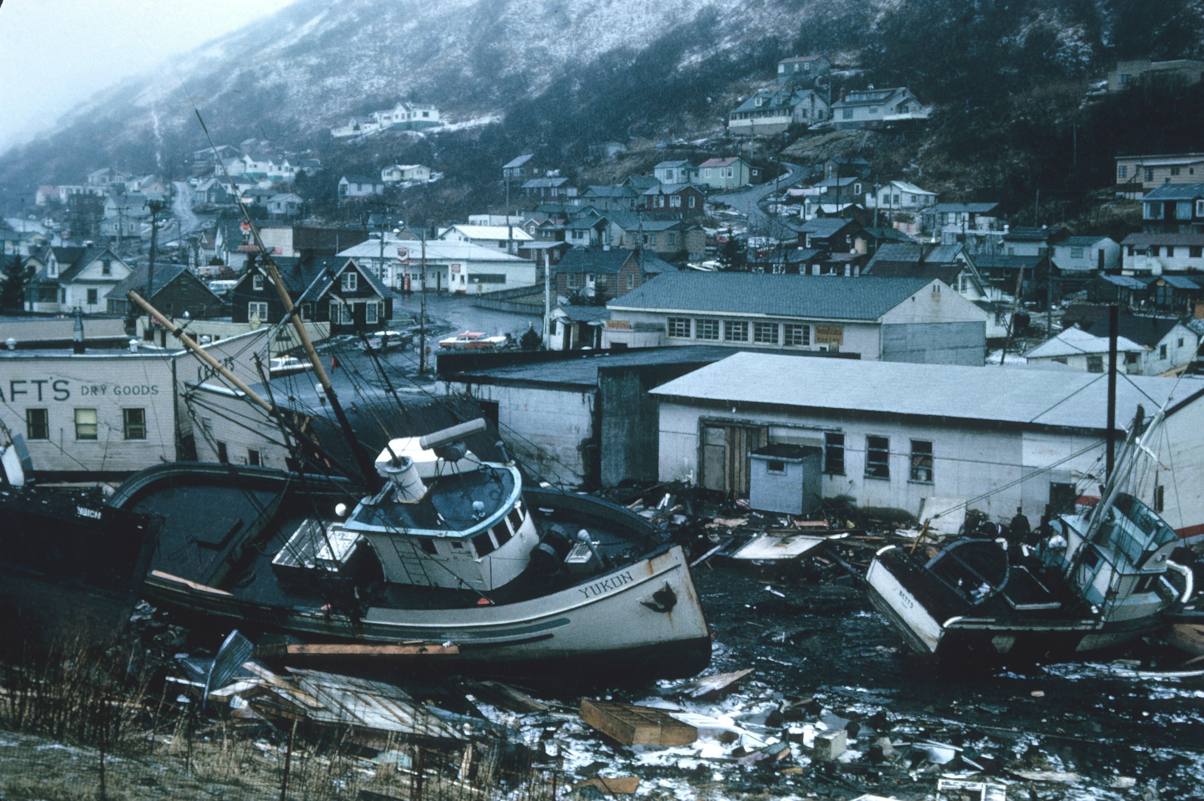Boats and debris in front of a hillside community