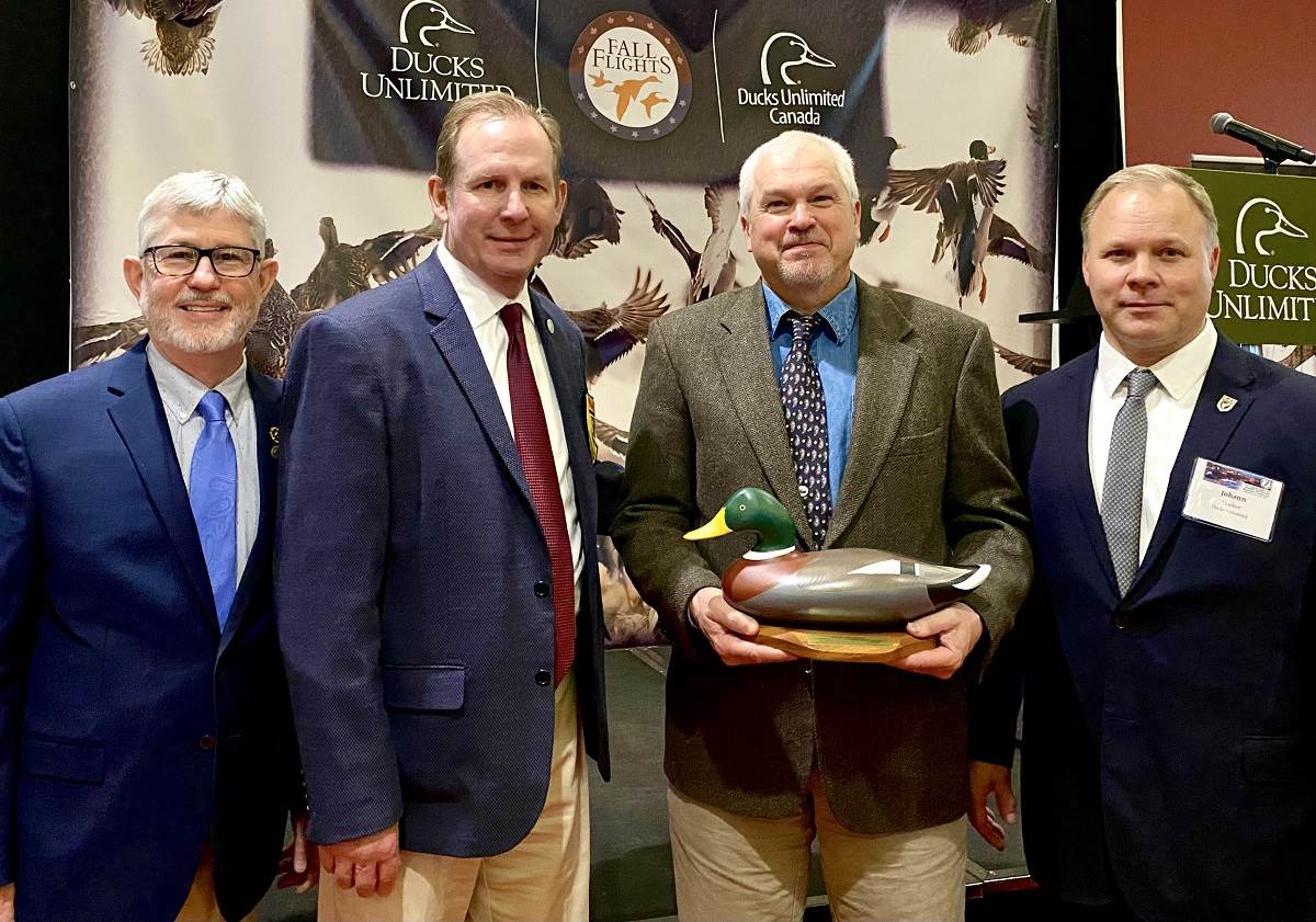 Mark Lindberg holds an award from Ducks Unlimited with three other men