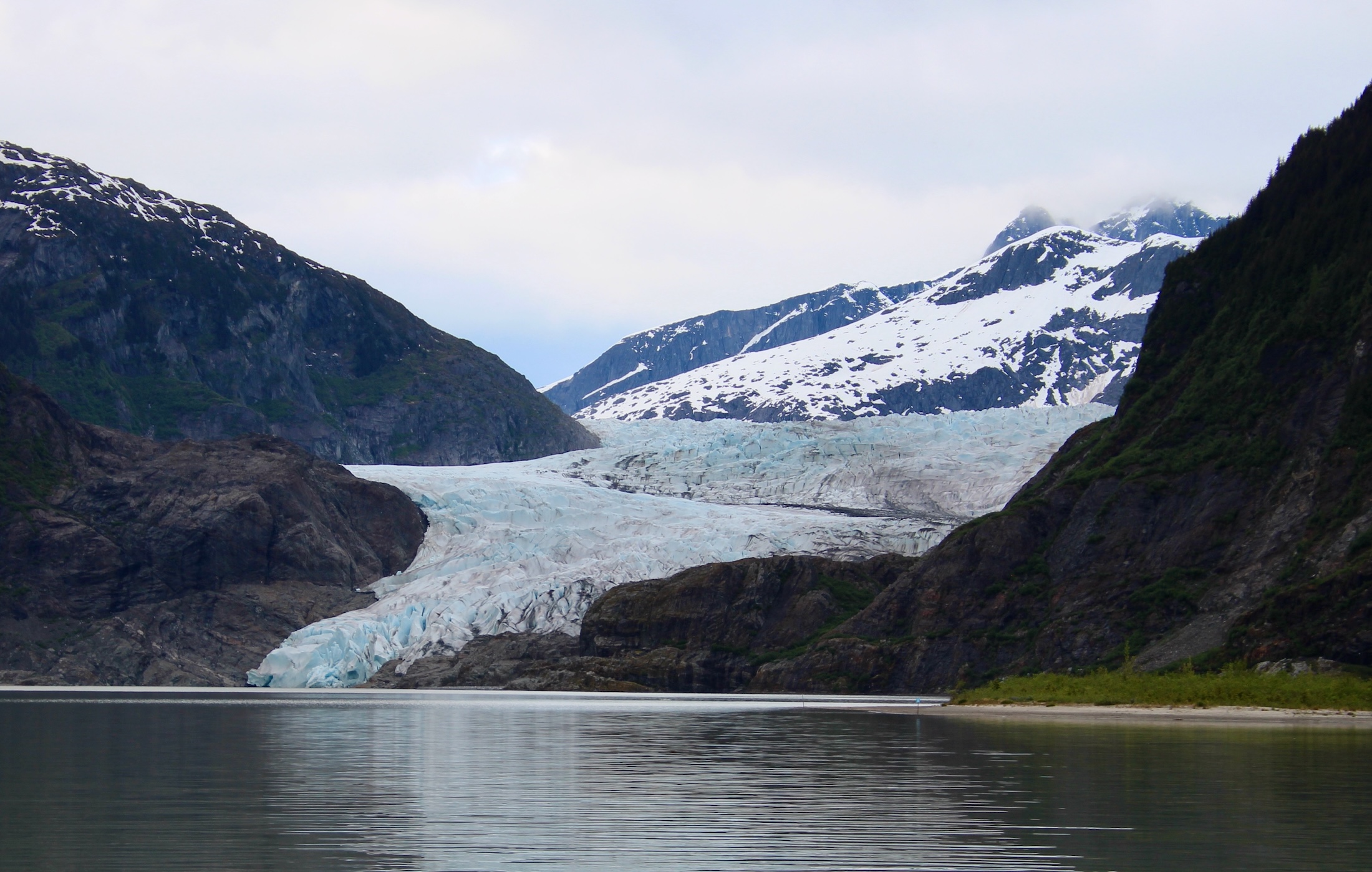 The toe of a mountainous glacier touches a lake.