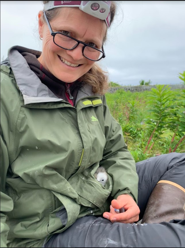 Smiling woman sits with a bird in her pocket