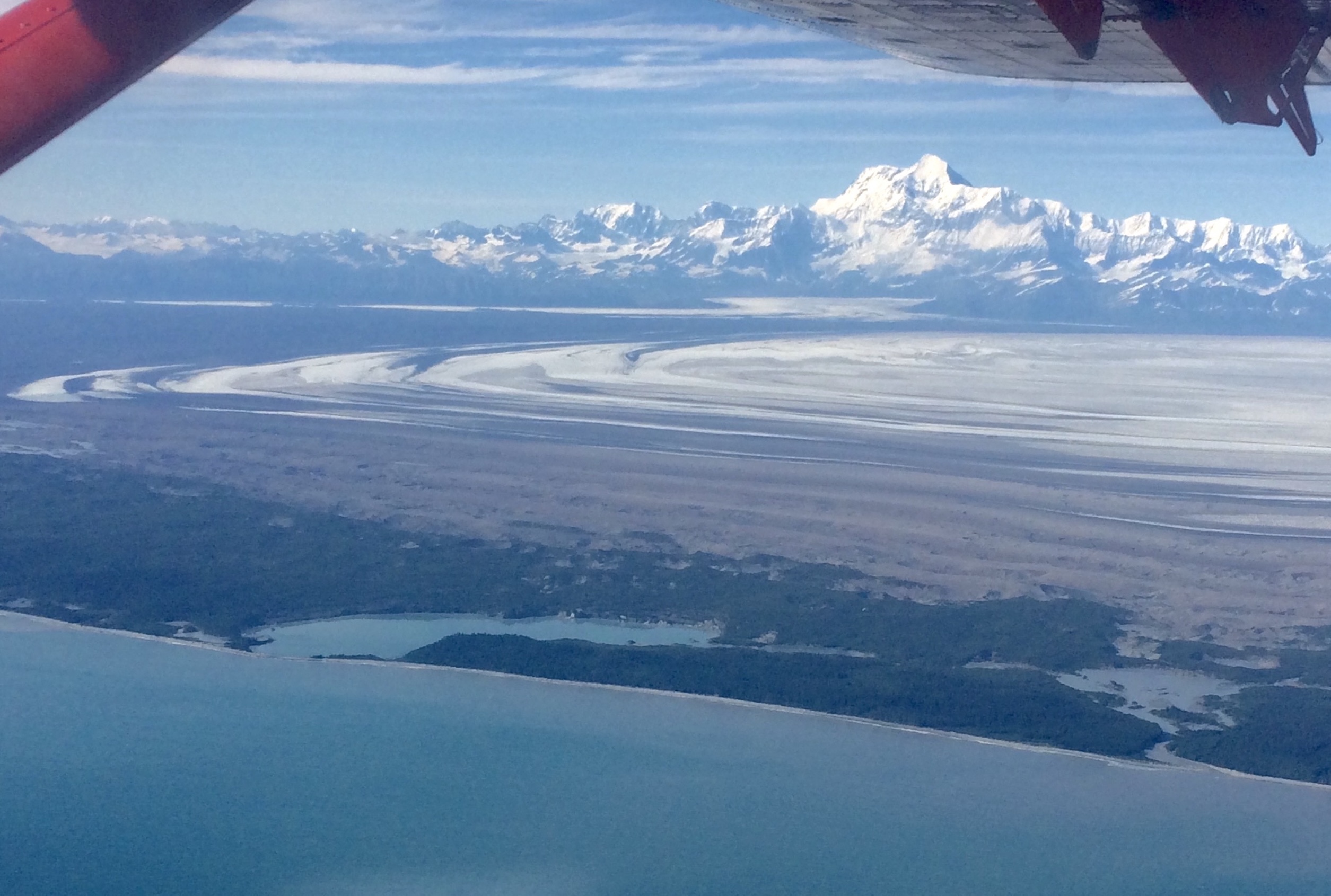 A wide flat glacier lies between a sea coast and a mountain range. 