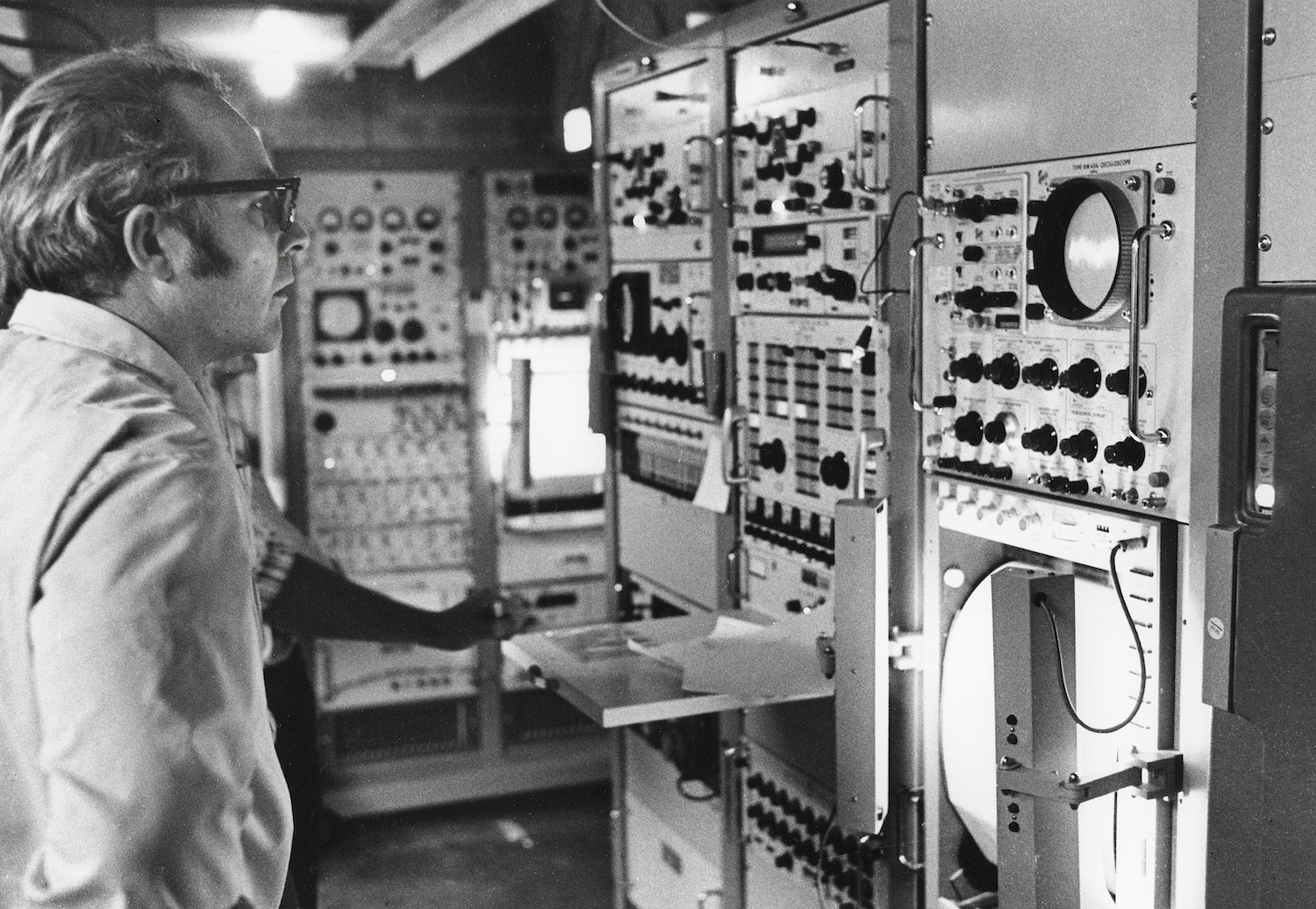 A man looks at a bank of scientific instruments.
