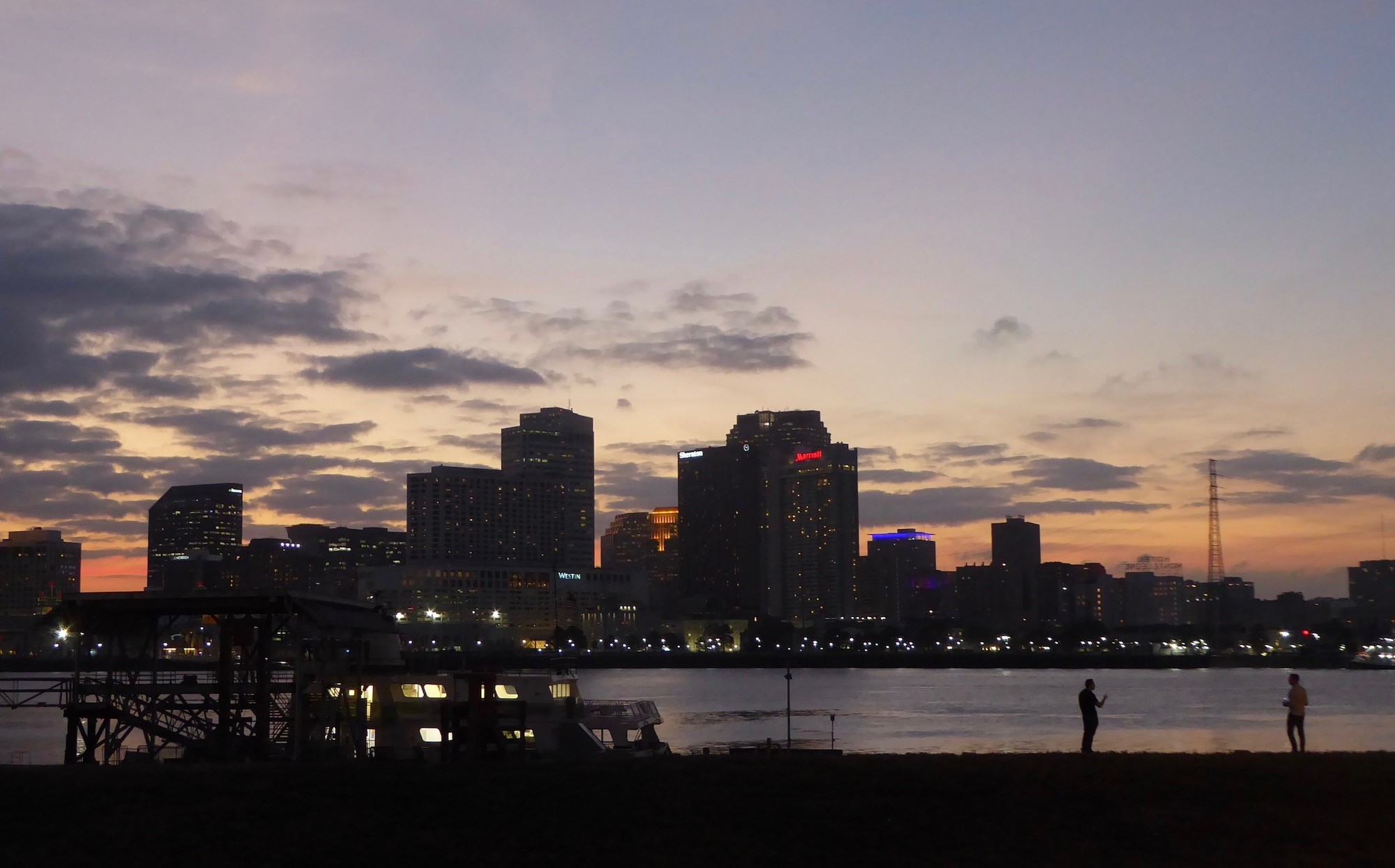 Sunset creates an orange background for the tall buildings that form the New Orleans skyline.