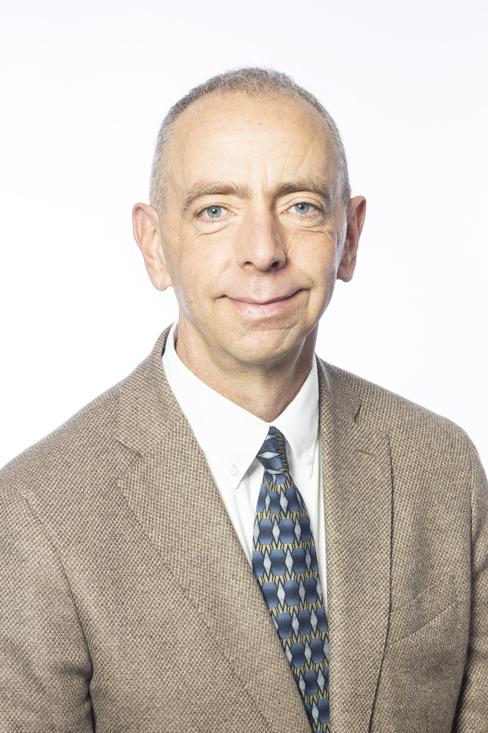 Owen Guthrie smiling in a tan suit