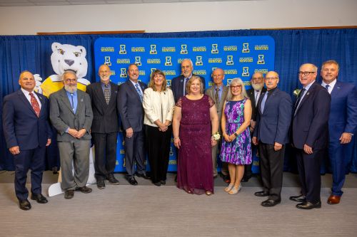 Previous UAF Business Leader of the Year award recipients, interim UAF Chancellor Mike Sfraga, and CBSM Dean Cameron Carlson, to her right, join Patty Mongold, the 2025 recipient, at the 8 Star Events Center in November.
