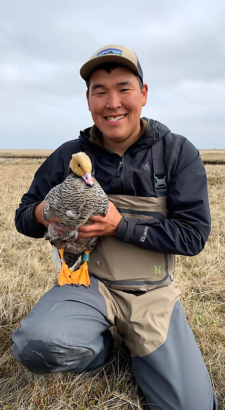 Smiling man on the tundra holding a duck