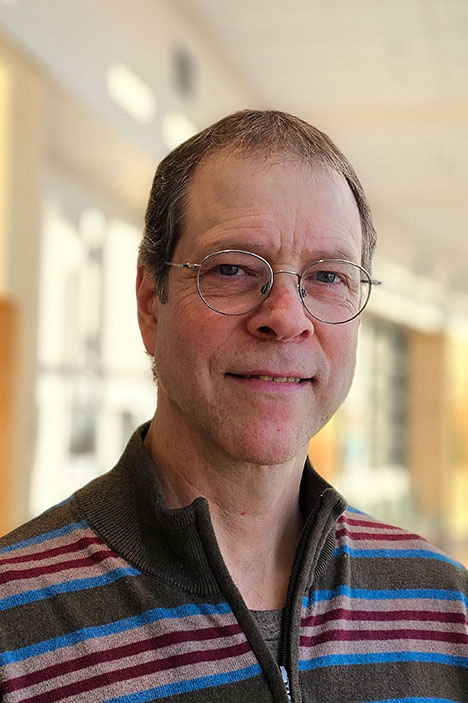 A portrait of a person wearing glasses and a striped shirt