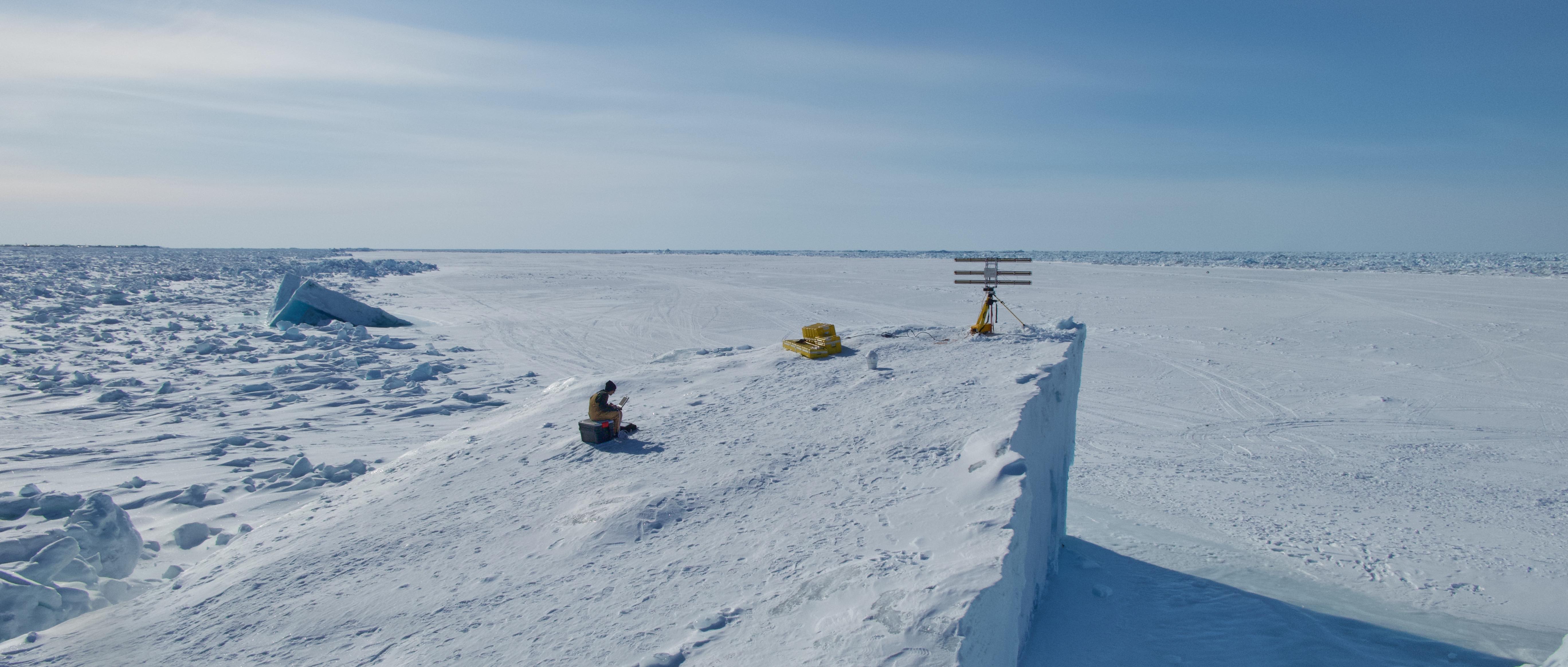 Graduate student researcher Emily Fedders sits on top of an ice island with the portable interferometric radar.