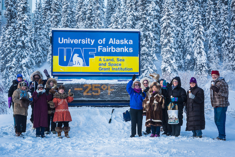 group of people in winter in front of -25 time and temperature sign