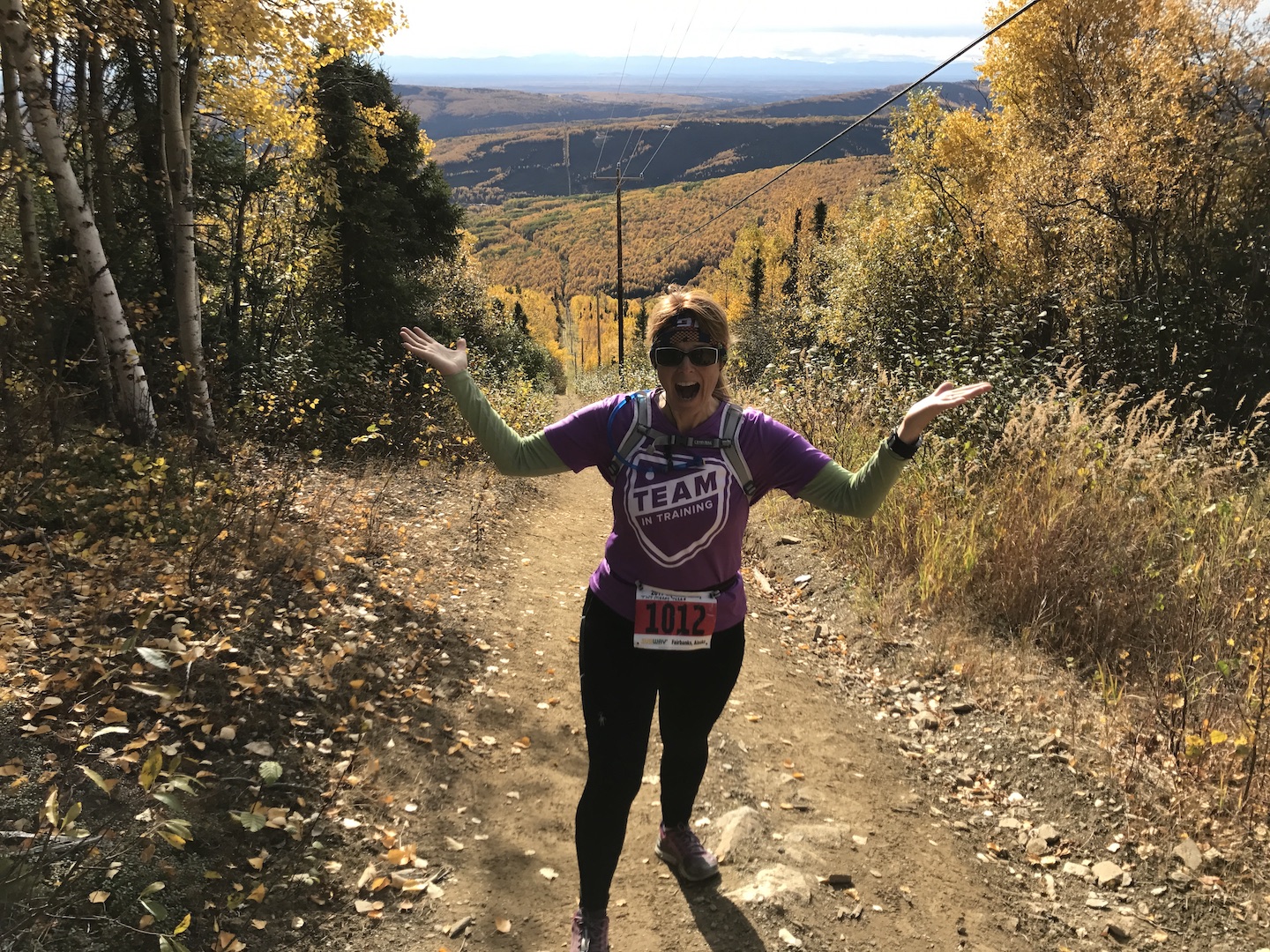 woman stands on a trail on a hill in autumn