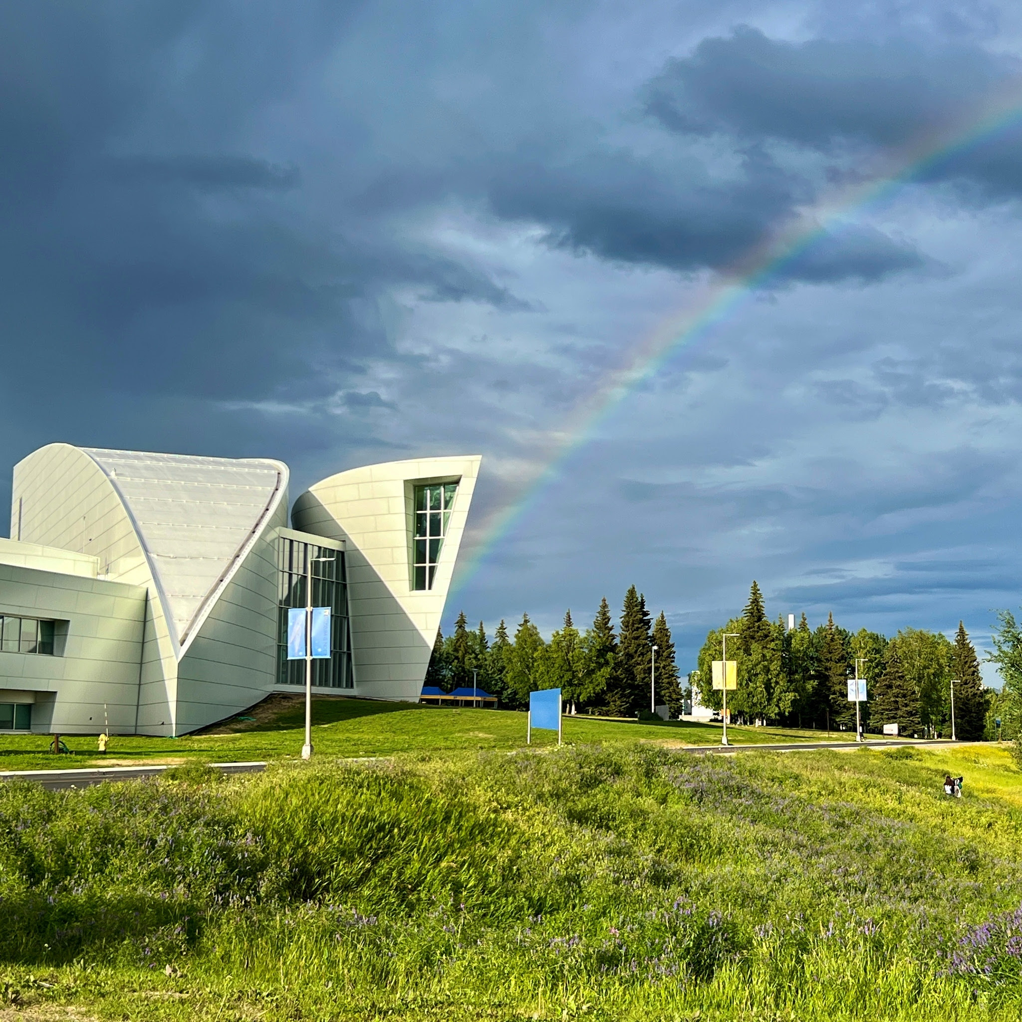 A rainbow appears next to the UA Museum of the North on a rainy day.
