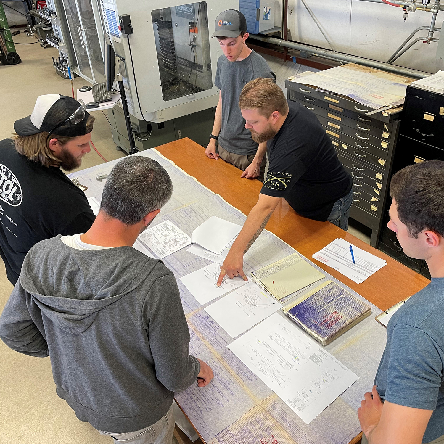 Several men look at engineering diagrams.