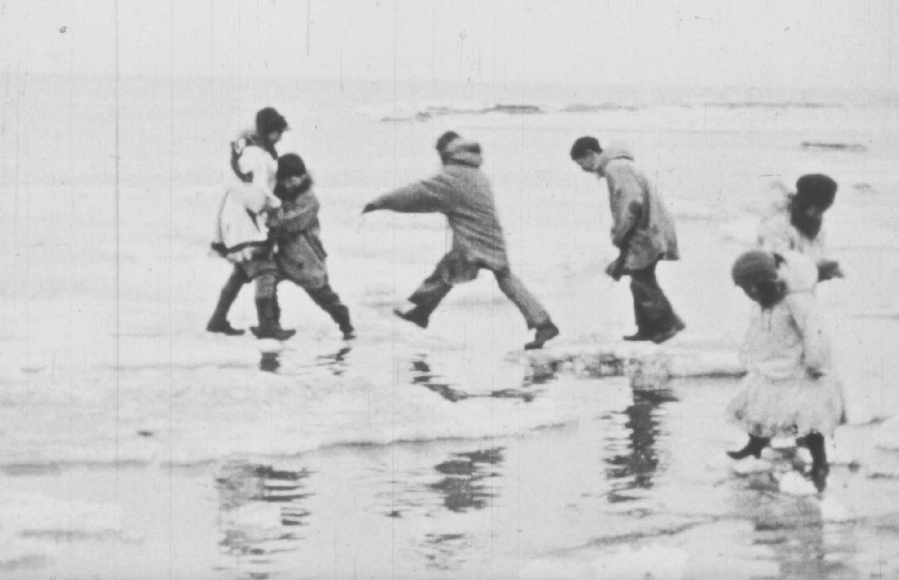 Young people jump between ice floes at Wales (Kingigin), Alaska, circa 1937. Still image from AAF-23809, Alaska Film Archives, University of Alaska Fairbanks.