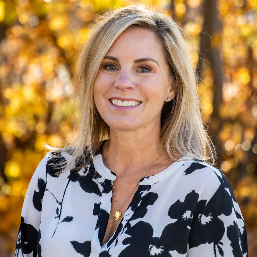 A woman wearing a black and white patterned shirt outdoors during fall.