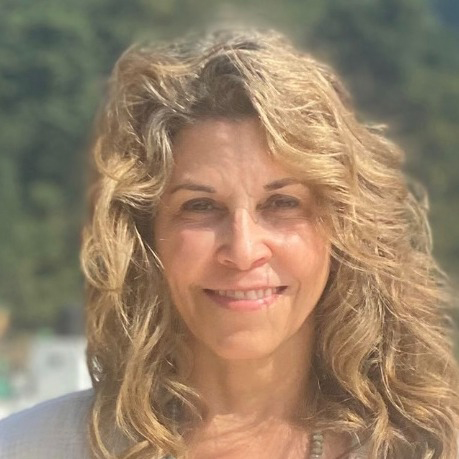 A woman with curly hair outside in the summer.