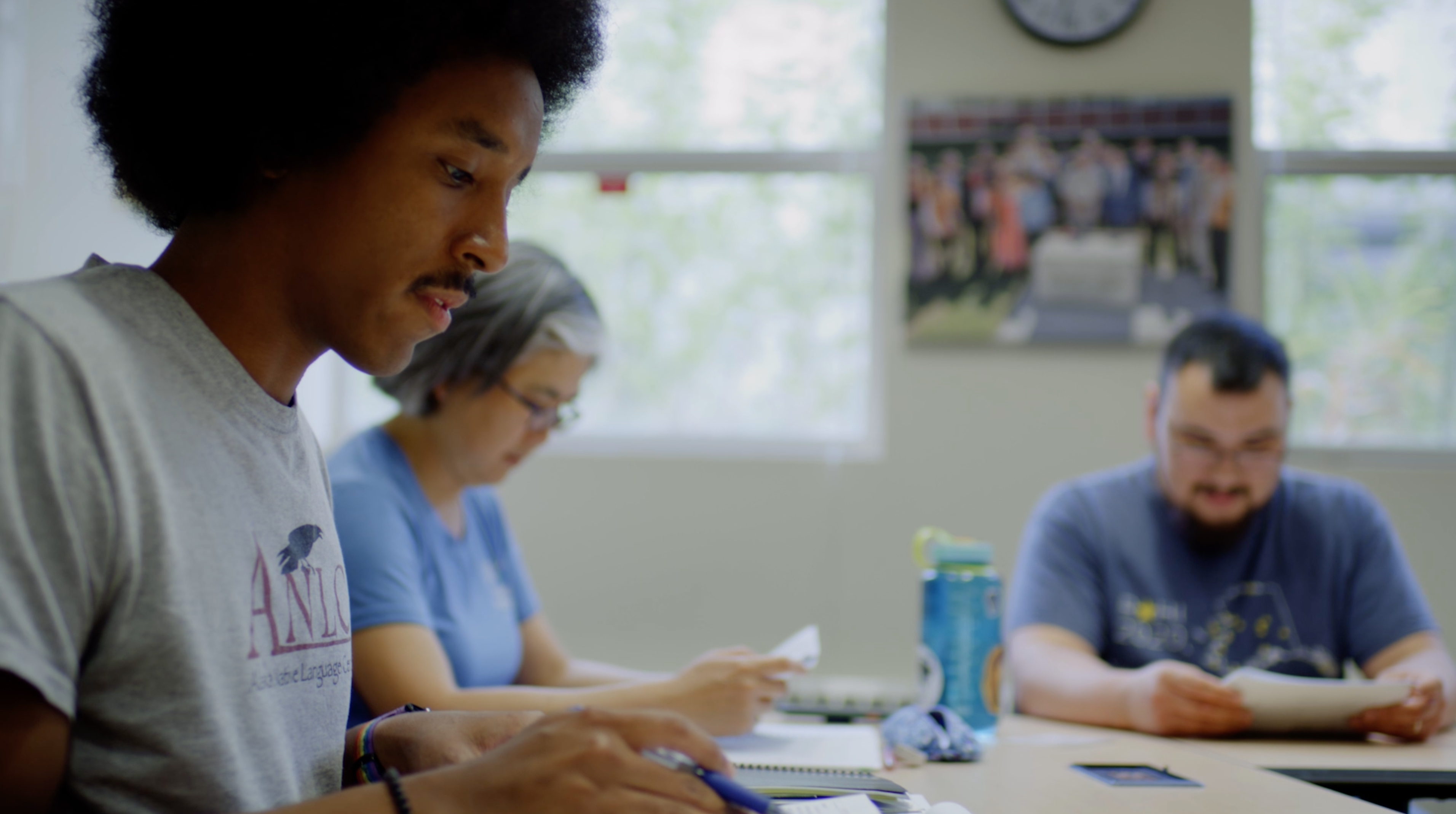 Three students at a table in a classroom looking at papers.