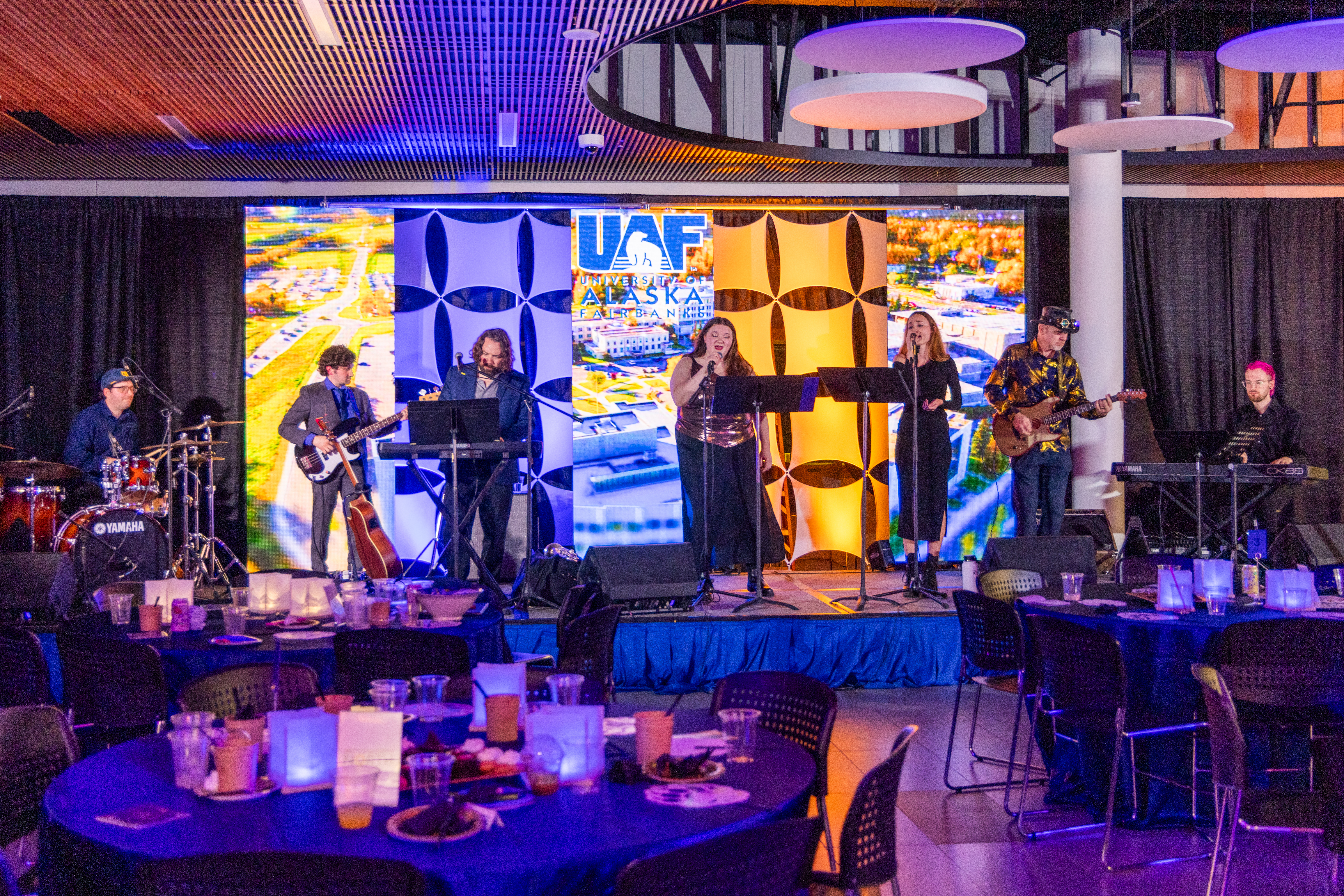 a band plays on a stage with a brightly lit backdrop