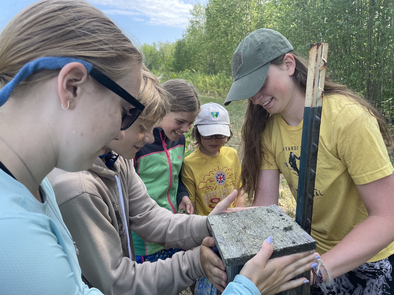A group of girls hold a birdhouse.