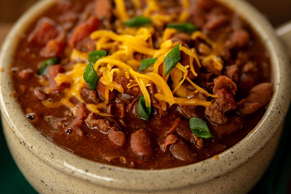 A bowl of chili topped with shredded cheddar cheese.