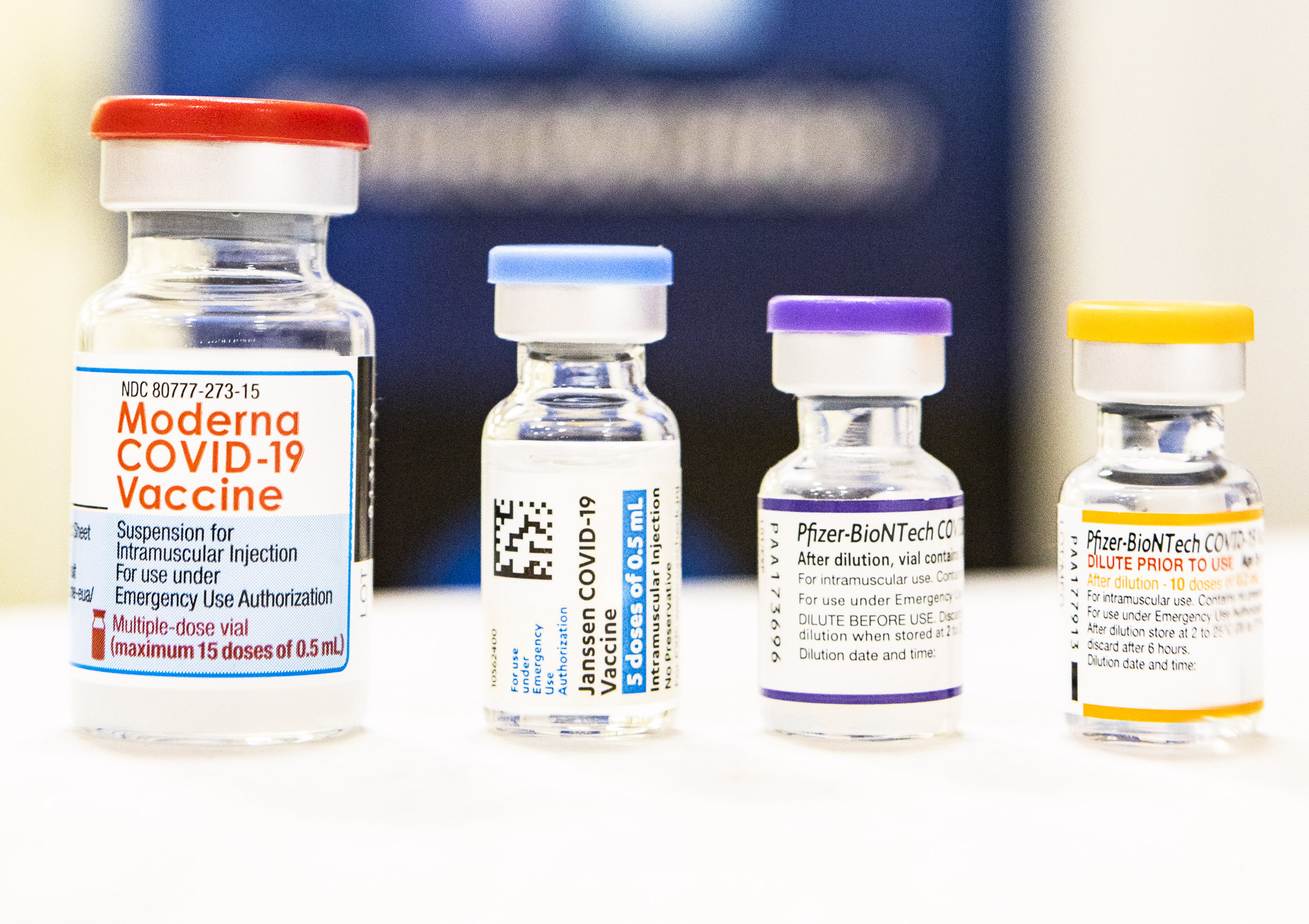 Four vials of COVID-19 vaccine with a blurred background.