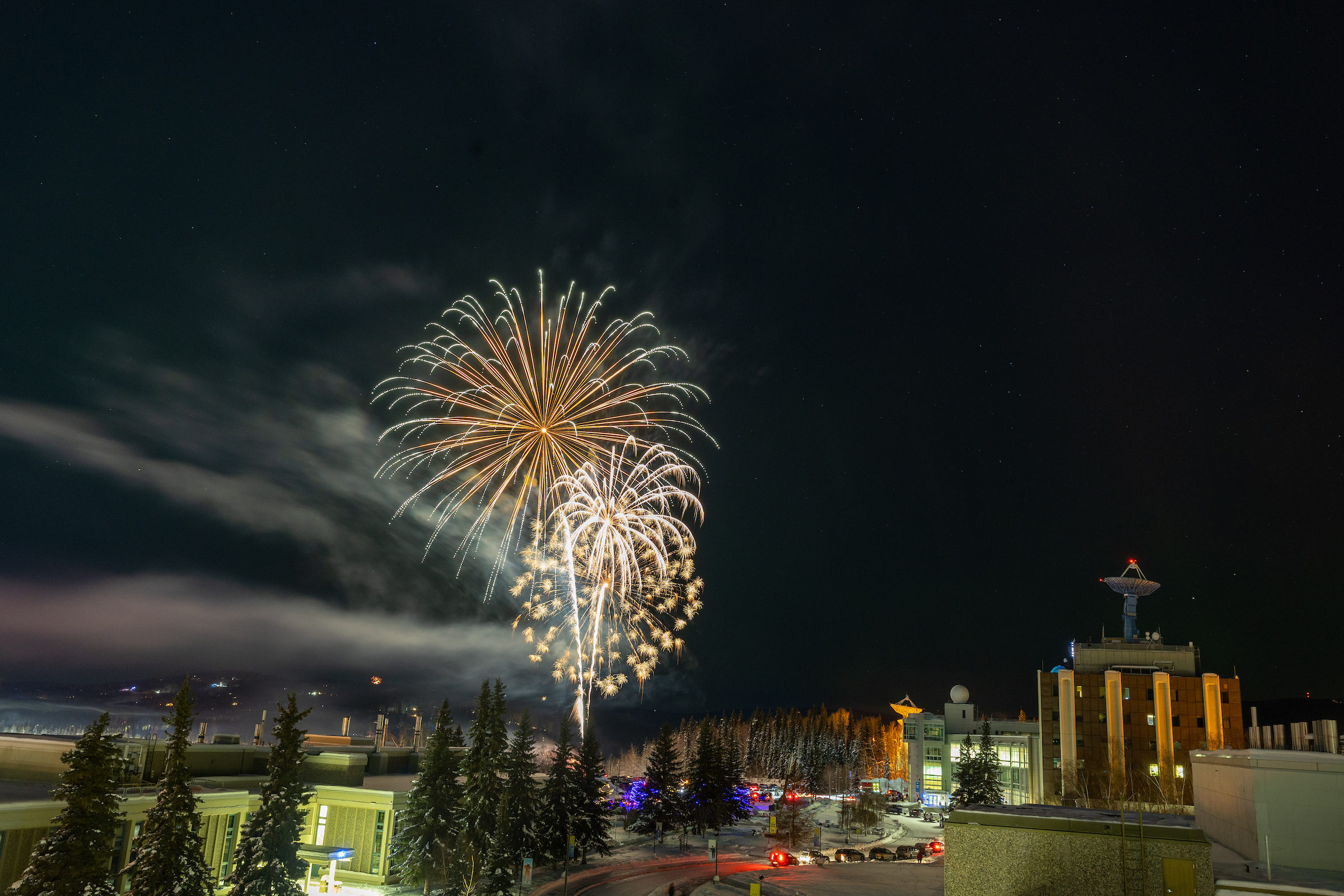 golden fireworks against a dark sky with vehicles in the foreground