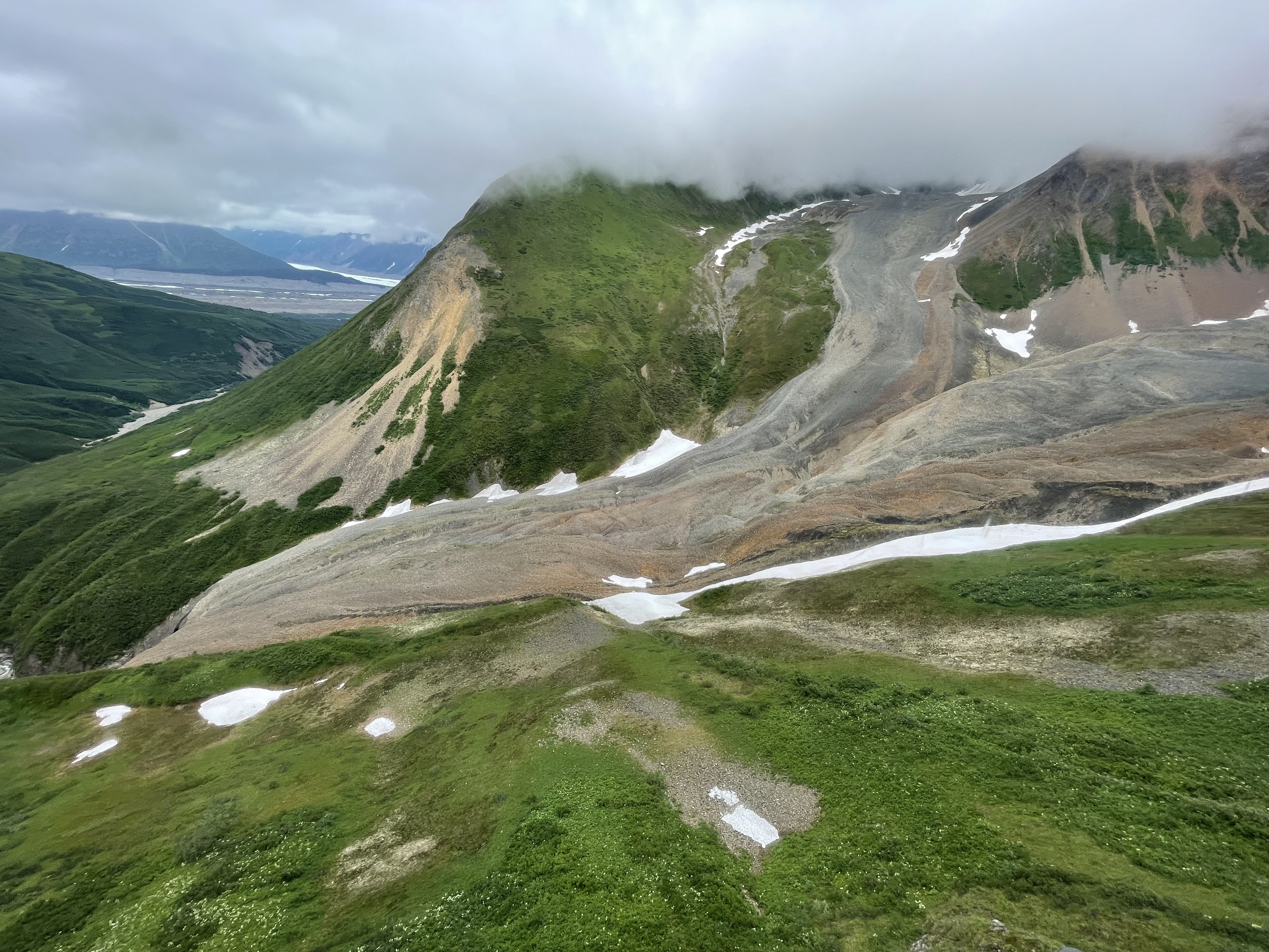 Green landscape featuring a large flow of rock and ice