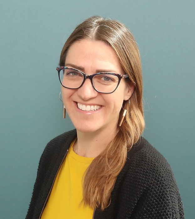 A woman wearing a yellow shirt with a black cardigan sweater.