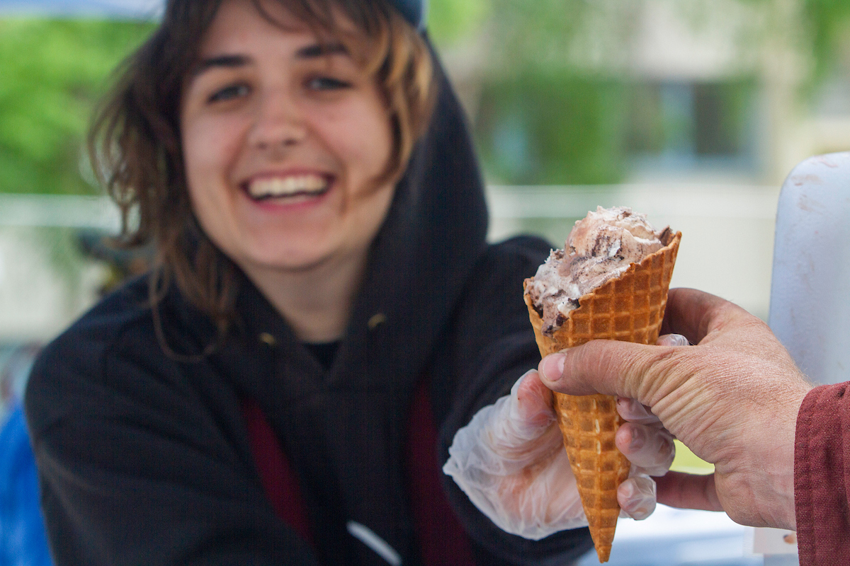 A woman scoops and serves ice cream during Ice Cream Thursday outside the Wood Center on the UAF campus.