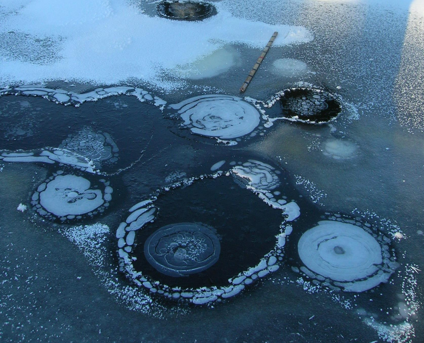 Photo depicting gas seeps in lake ice.
