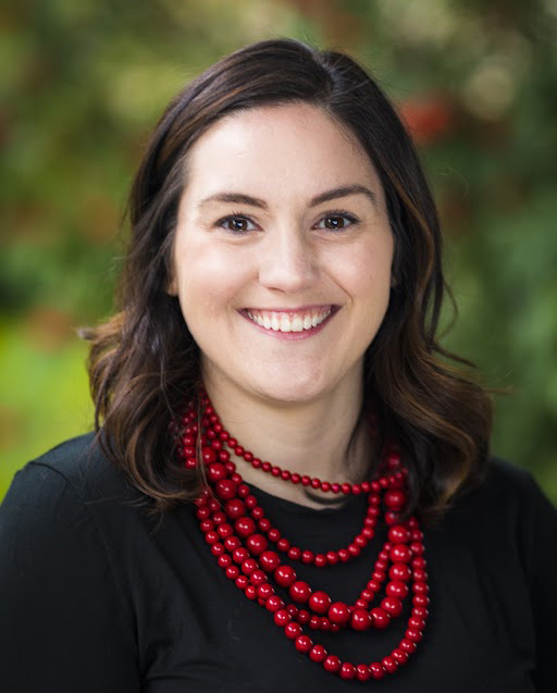 A woman wearing a black shirt and a red necklace.