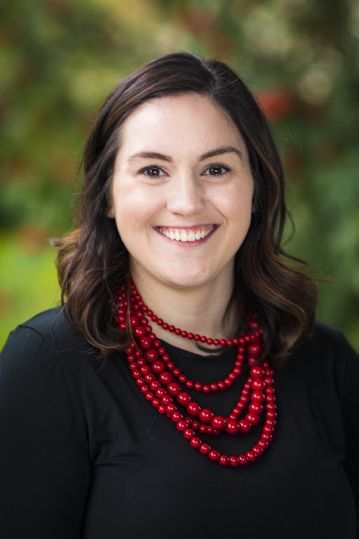 A woman wearing a black shirt and a red necklace.