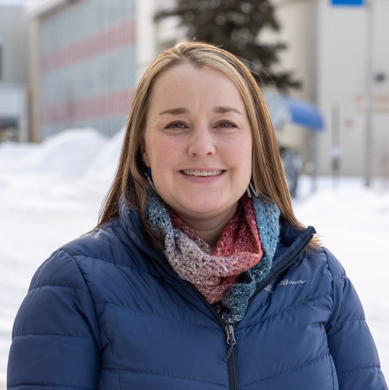 A woman wearing a blue puffy jacket outdoors in winter.