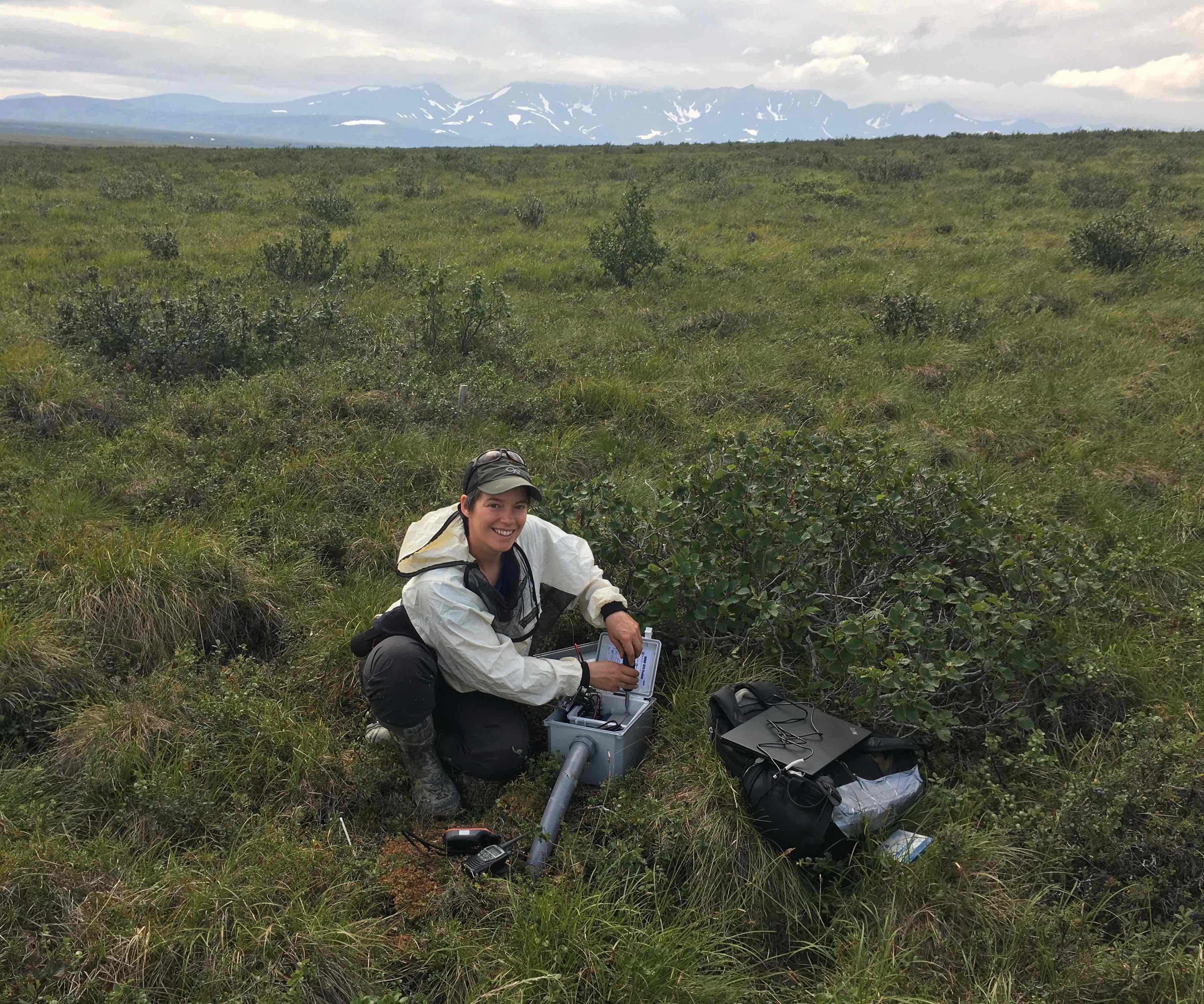 A woman works on scientific equipment on the tundra