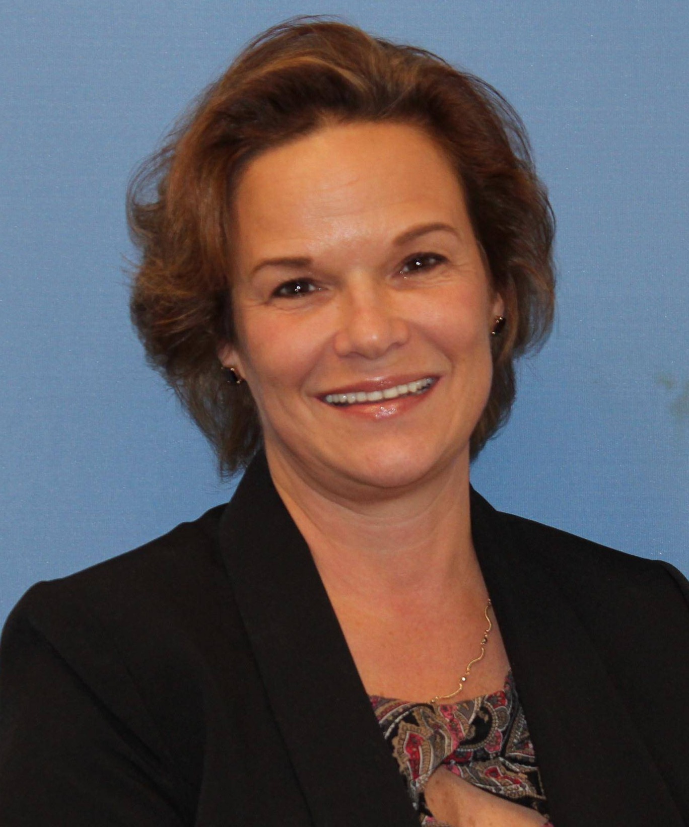 A woman wearing a black blazer jacket with a patterned blouse.