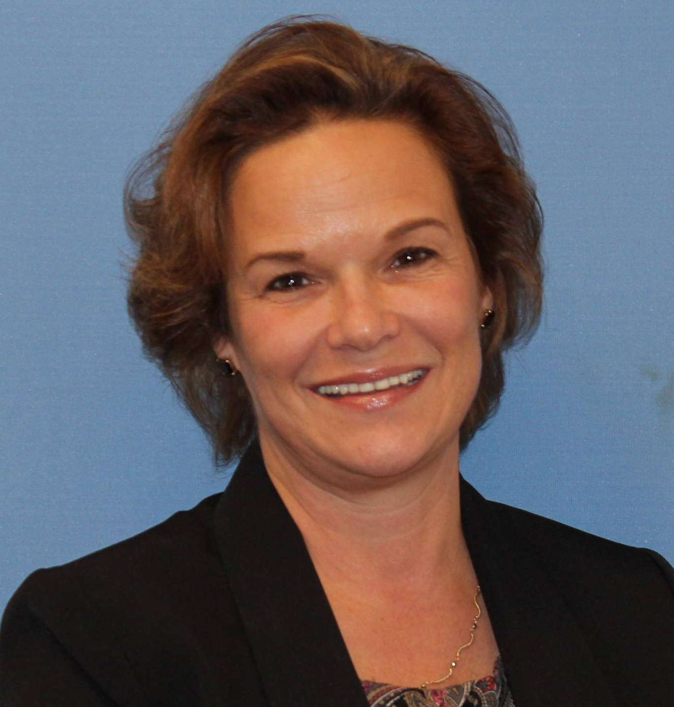 A woman wearing a black blazer jacket with a patterned blouse.