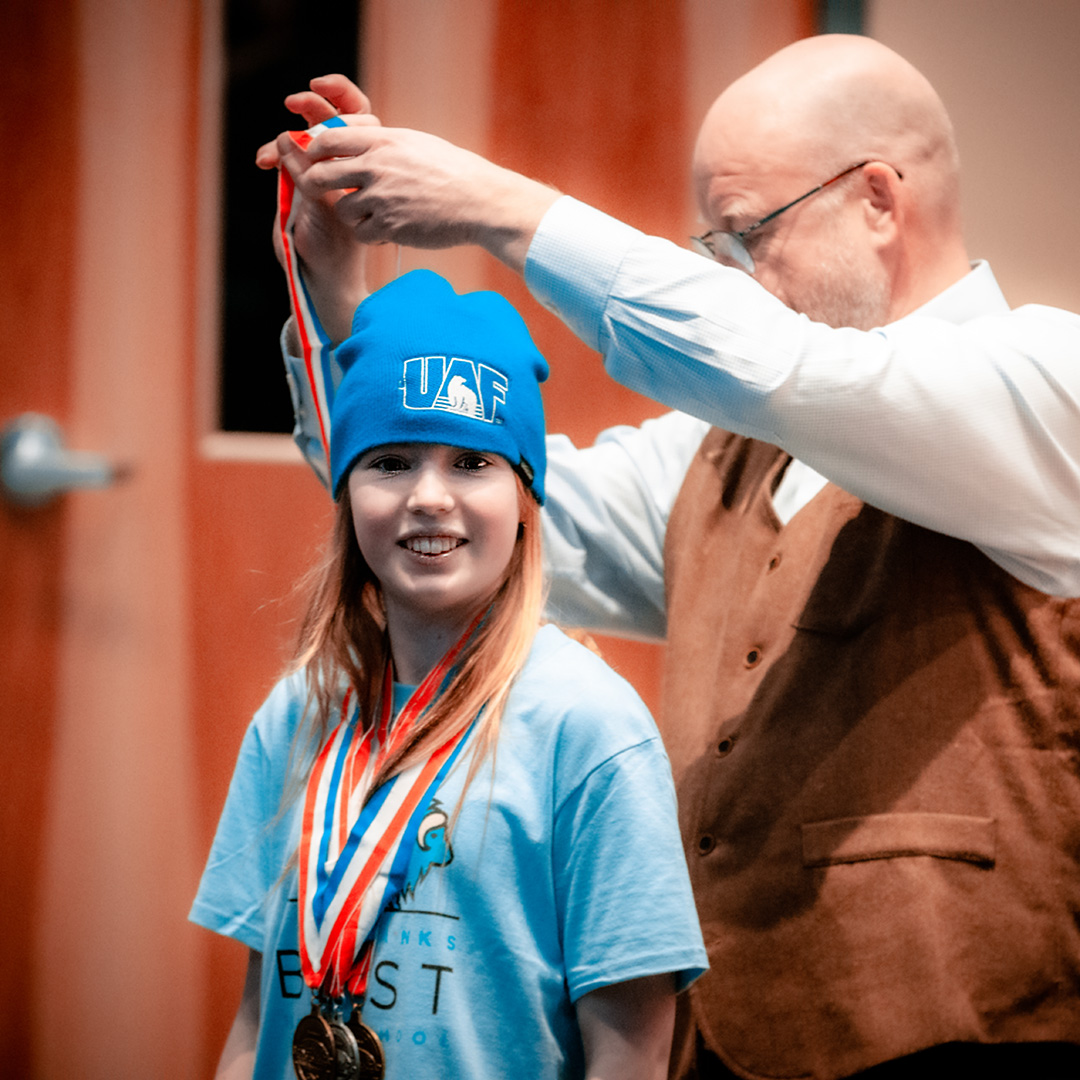 A participant receives medals during the 2023 Science Olympiad award ceremony in February. Photo by Greg Russo.