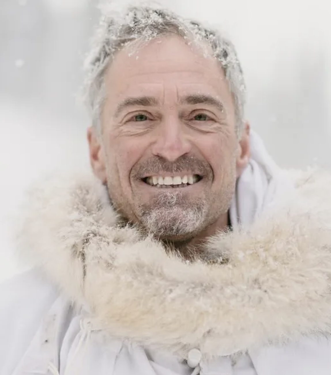 head and shoulders portrait of a man in a white, fur-trimmed parka