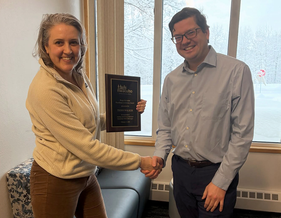 Teddi Walker, the director of UAF Residence Life, receives the Roger Frichette Excellence in Service Award from Mathew Mund, UAF Residence Life’s business operations manager and past president of the Northwest Association of College and University Housing Officers, during a staff meeting on Feb. 19, 2026.