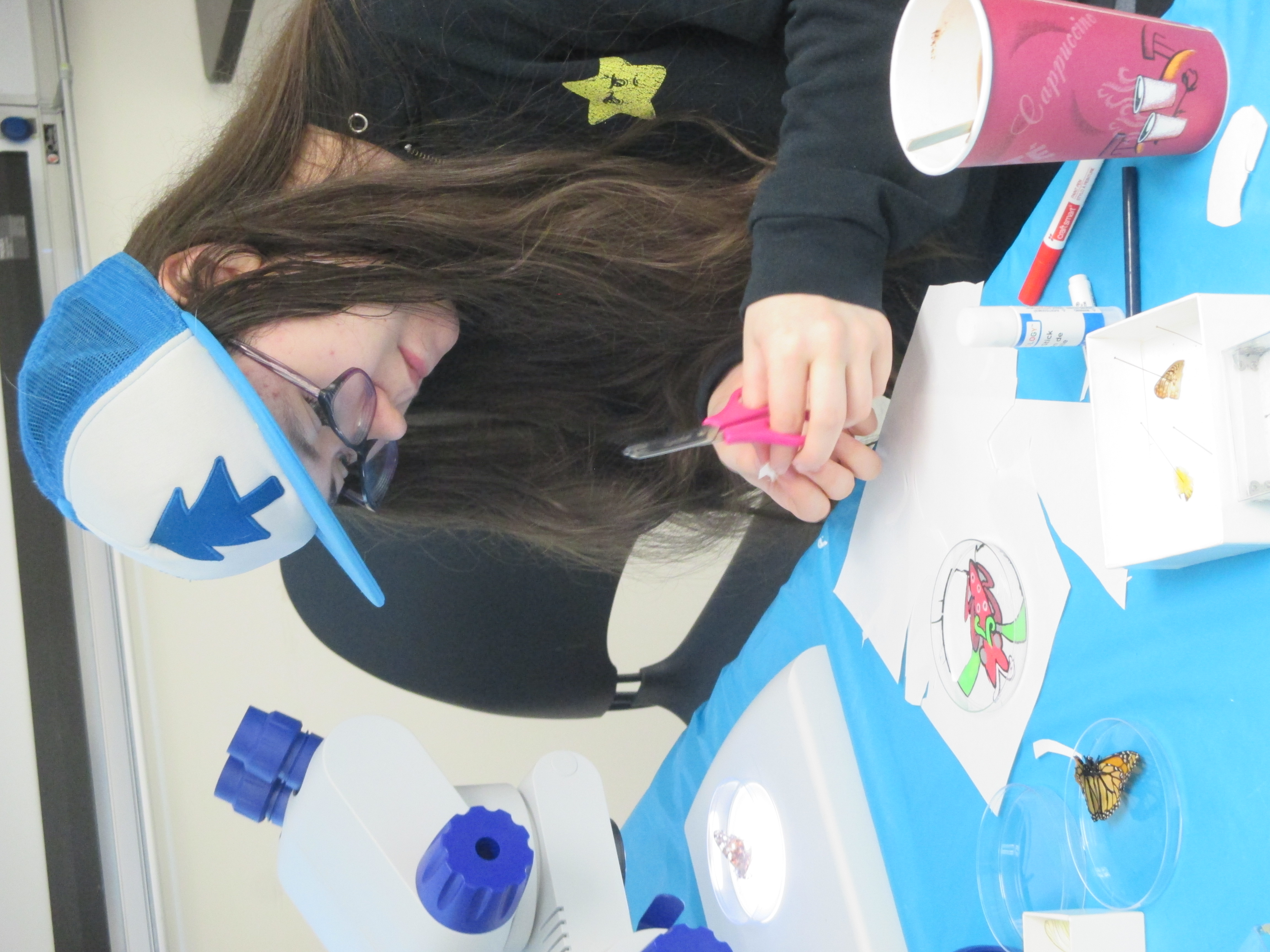 a teenage girl uses scissors to cut out a paper butterfly