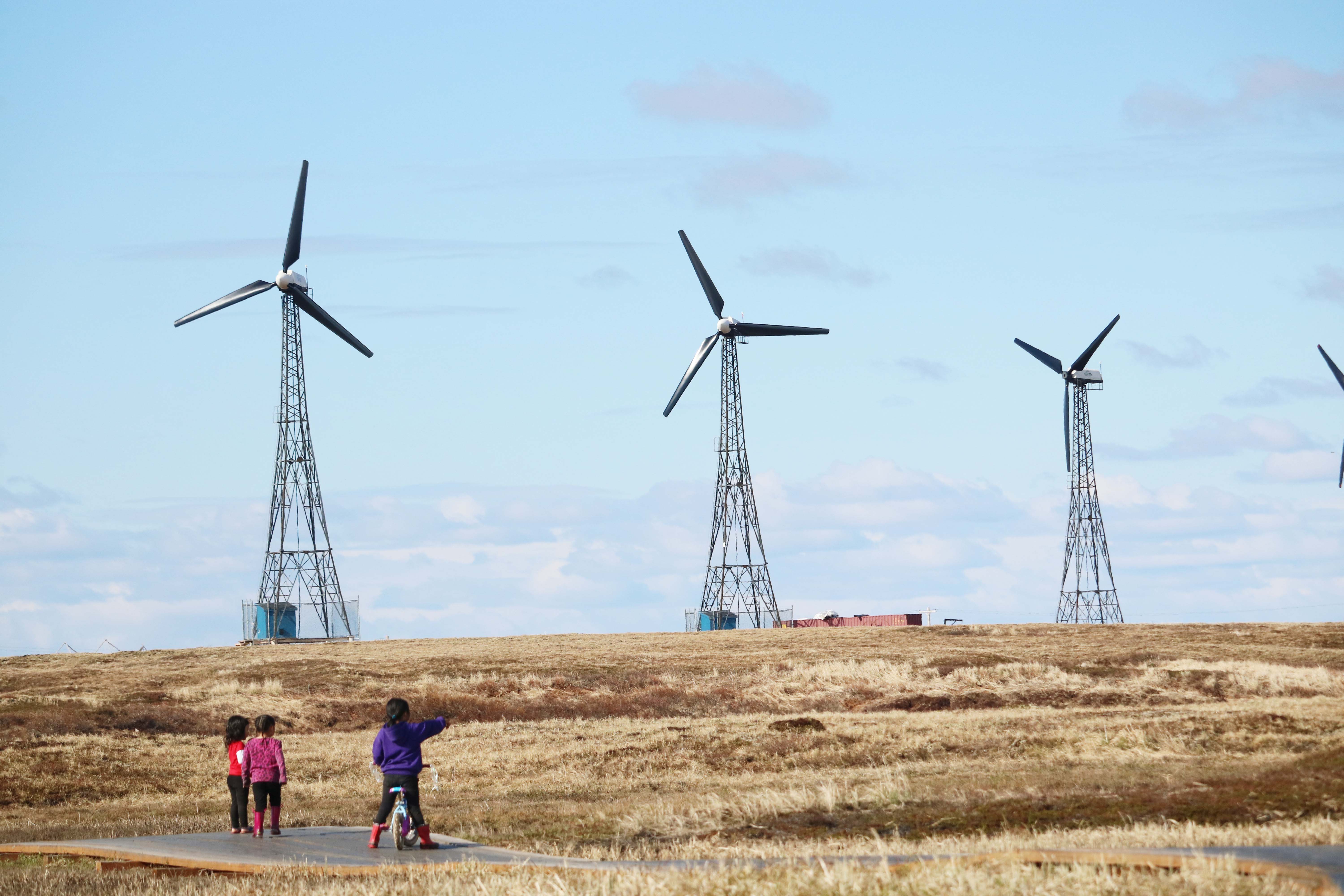 Children point to a wind farm