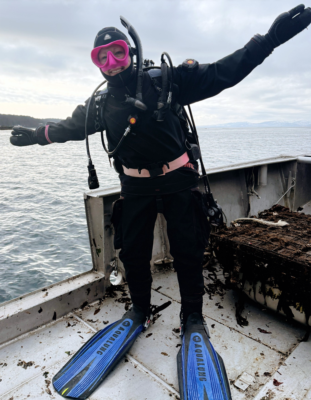 Woman wearing snorkeling gear, Missy Good, stands on the deck of a boat in the ocean