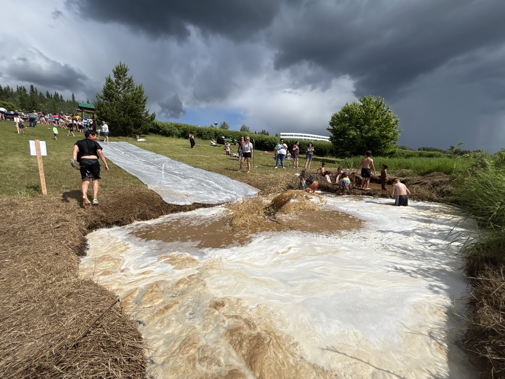 Children wade in a muddy pool after slding down a hillside.