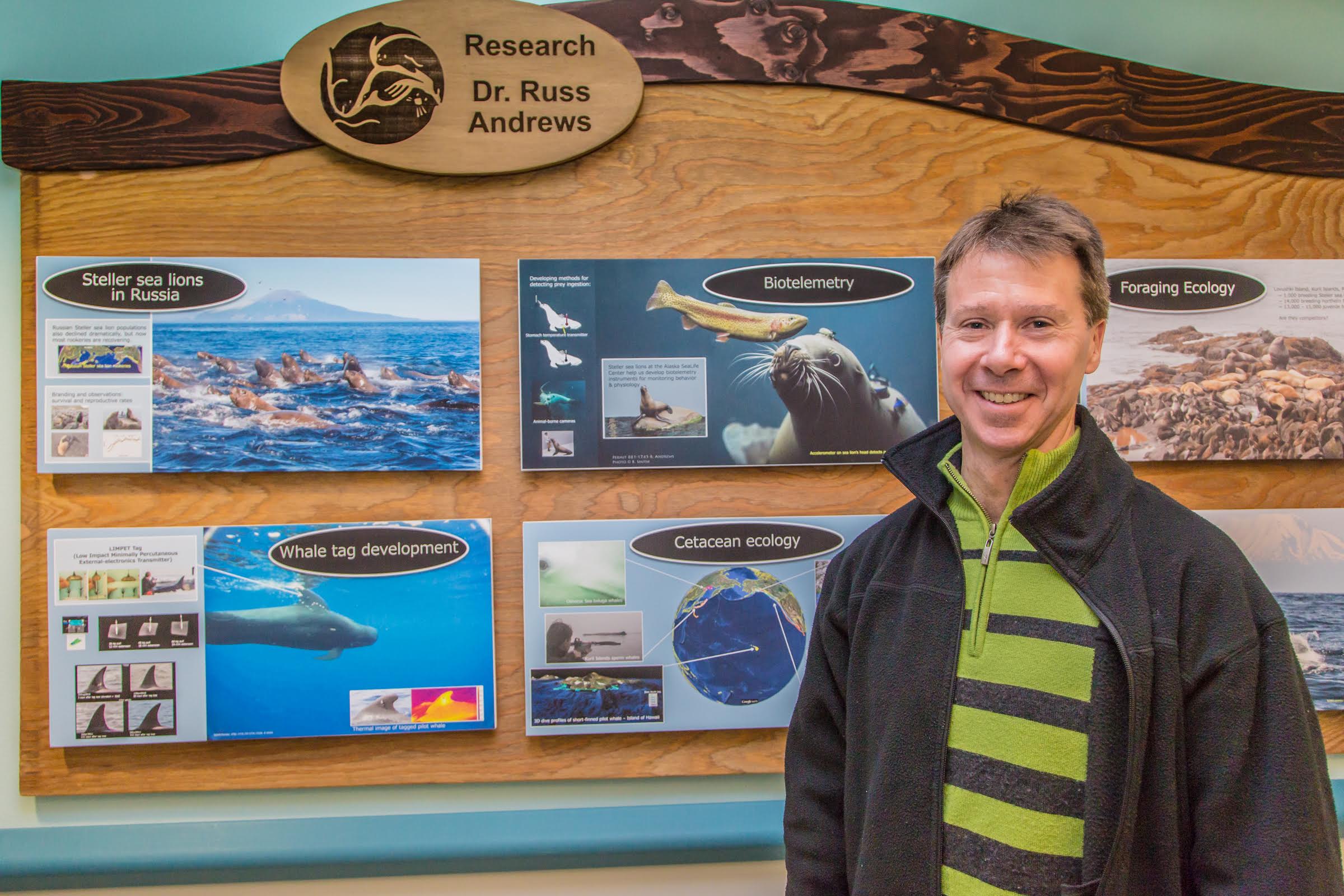 Research Assistant Professor Russ Andrews stands by one of his posters on display at the Alaska Sea Life Center in Seward.