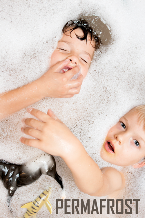 Two kids in a bubble bath, one holding his nose
