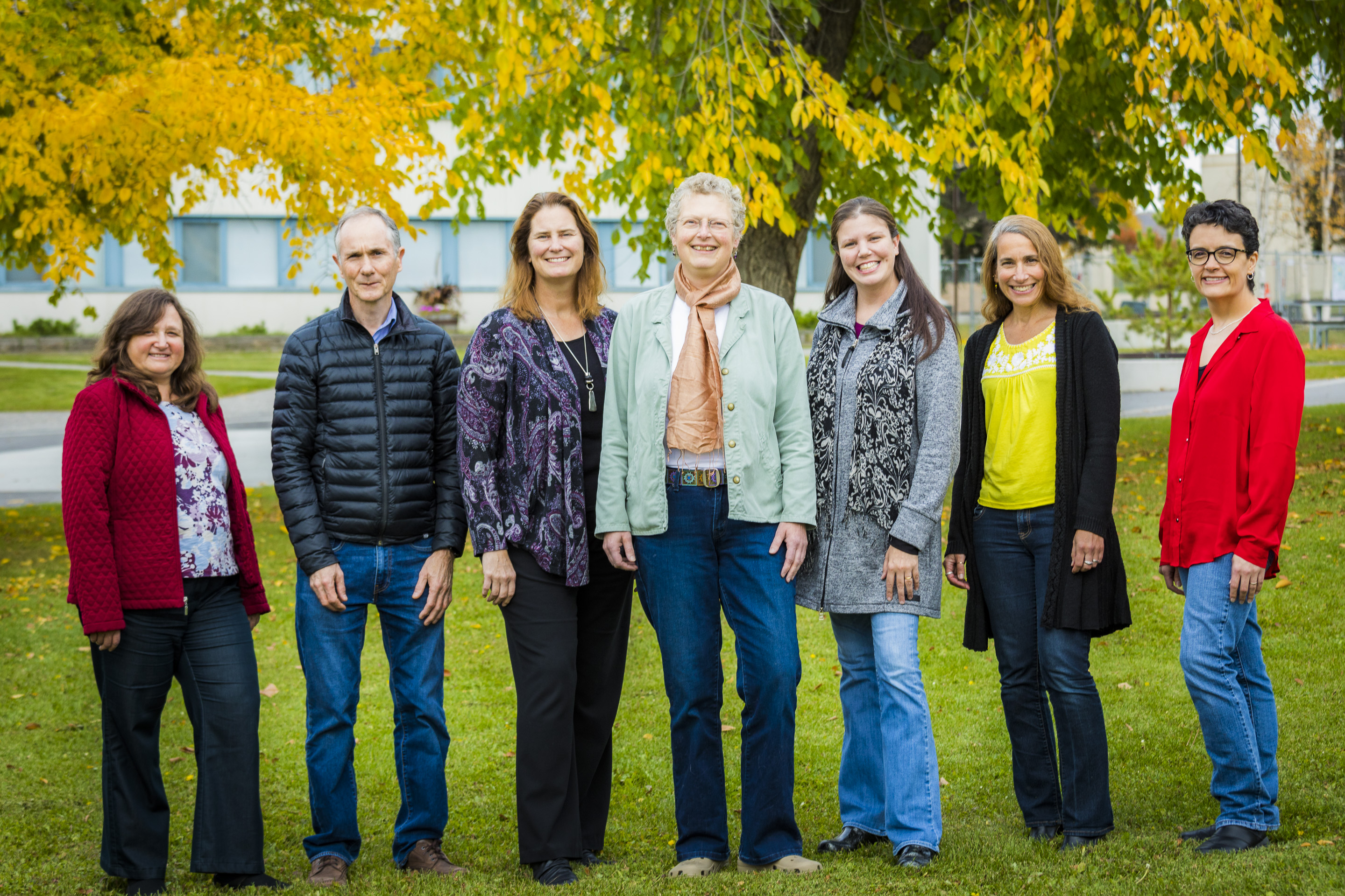 The Psychology Department staff poses as a group in front of autumn leaves | UAF Photo by JR Ancheta