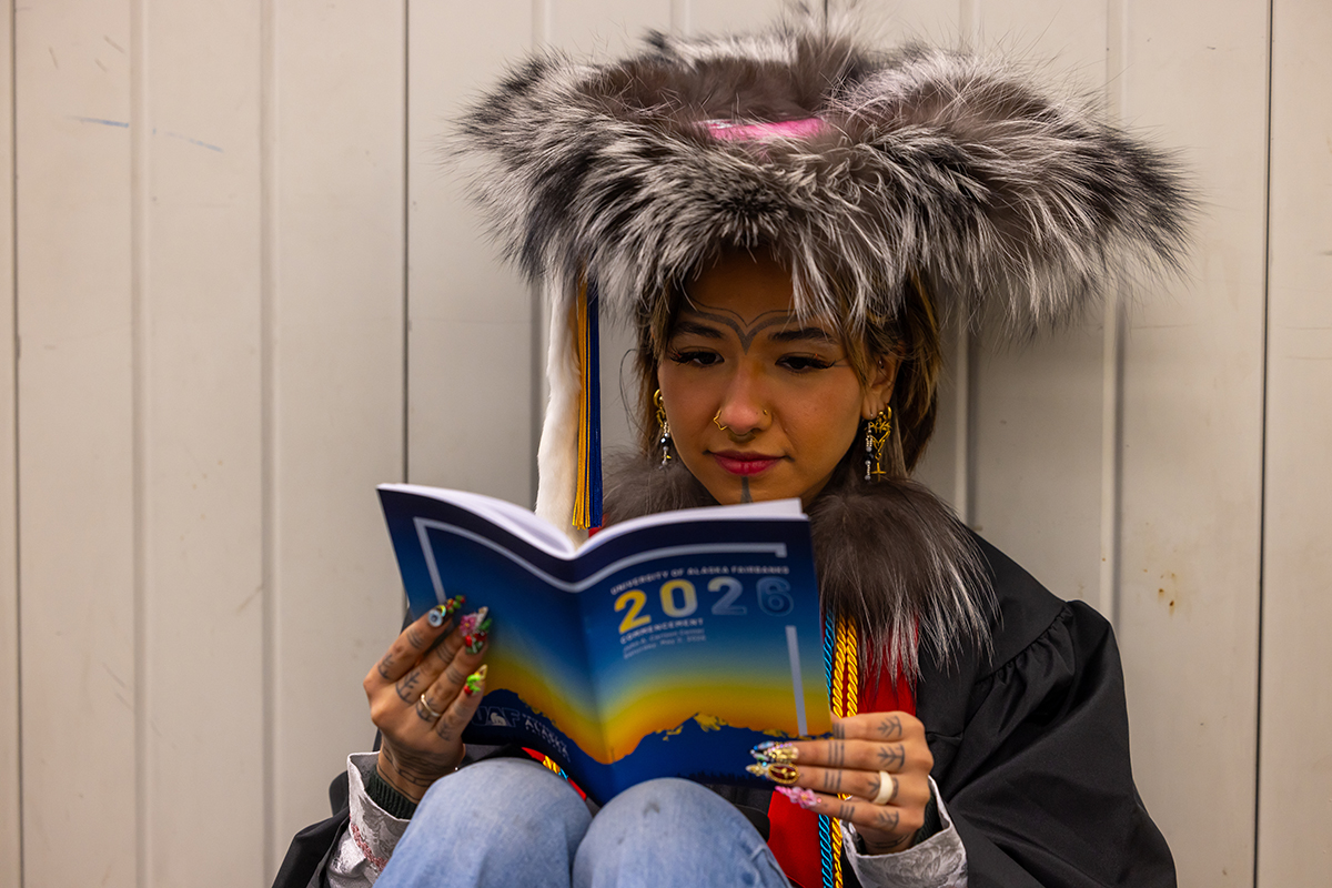 Shooka Dalilak reads the 2026 UAF Commencement program. UAF Photo by Eric Engman