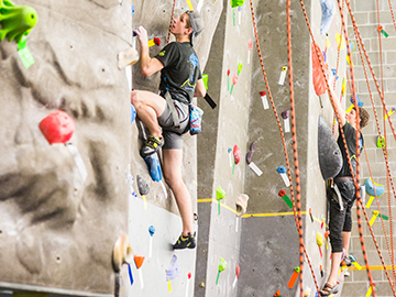 Two climbers climbing at the UAF SRC indoor rock climbing wall.