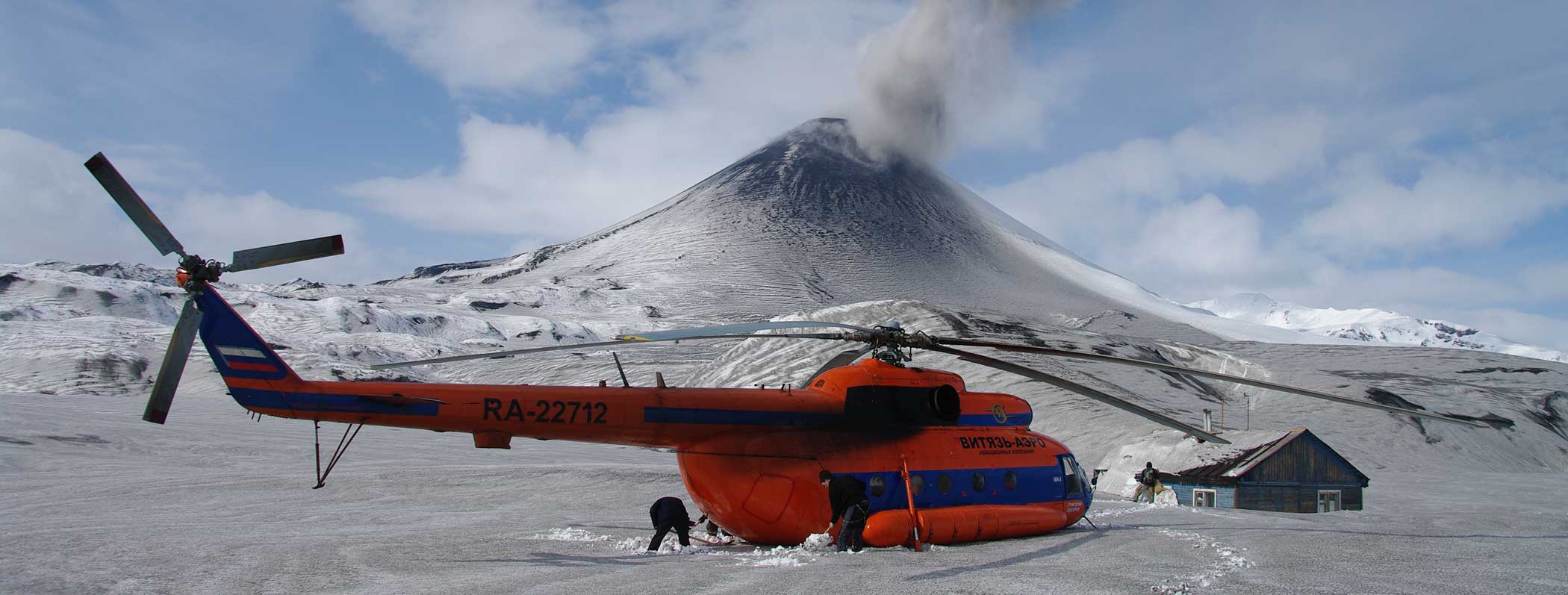 A helicopter landed on the snow outside a remote research camp near a smoking volcano